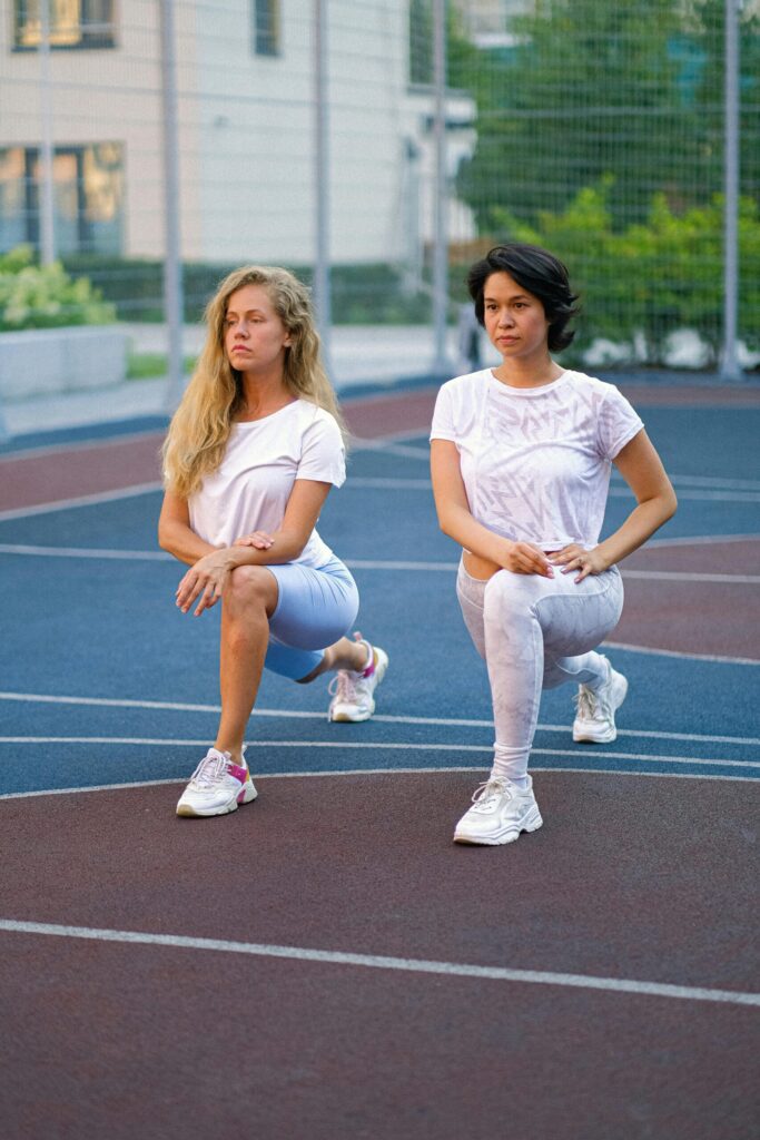 pexels-photo-5262741 Confident ladies stretching legs on sports ground
